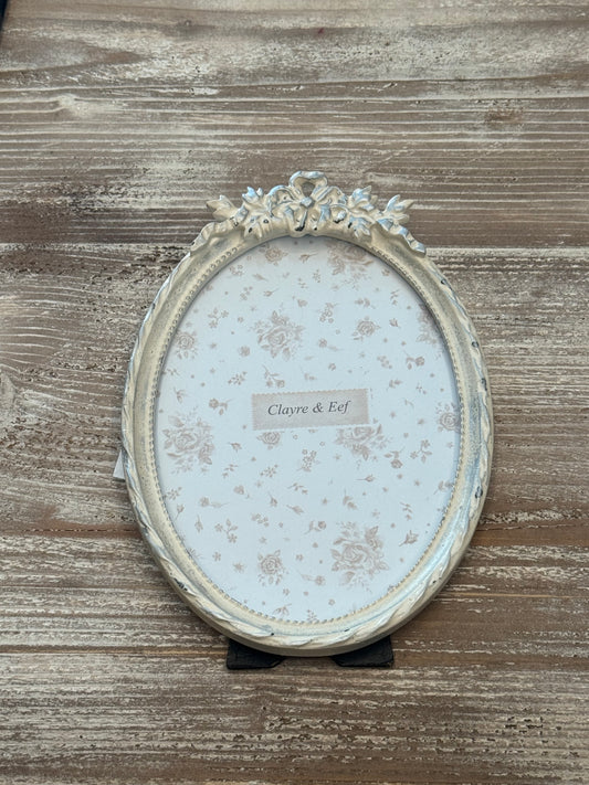 Cornice ovale bianca con decorazione a fiocco